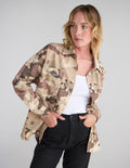 Woman wearing an oversized tan and brown camo shacket with button-down closure and 'What a Friend in Jesus' text