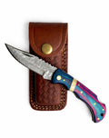 Titan Ranger Damascus folding knife in silver and blue, displayed on a tactical backdrop.