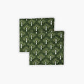 Set of two Zeenat chive green cotton table napkins with white botanical hand-block print patterns on a dining table.