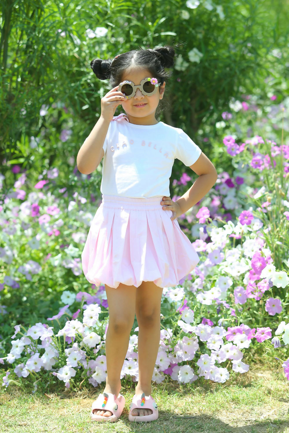 A girl wearing a white crew-neck cotton tee paired with a pastel light pink A-line mini skirt in a casual setting.