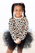 Young girl wearing a beige leopard print long sleeve sweater with a black tulle skirt