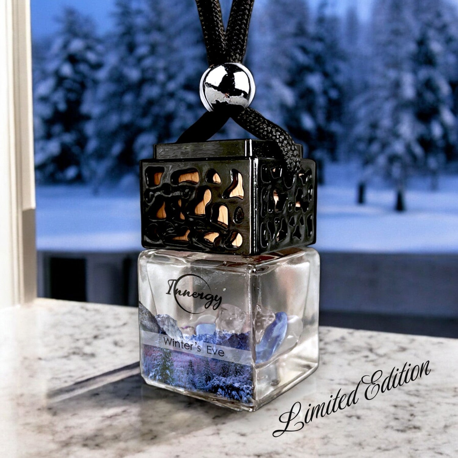 Limited edition Winters Eve crystal-enhanced glass car oil diffuser with black wooden lid hanging against a snowy winter background.