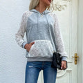 A woman wearing a grey long sleeve sweatshirt with white lace detailing on the sleeves and a matching lace front pocket.