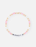 Close up of a stretch beaded bracelet spelling WONDER with pink and clear crystals and gold-tone spacers on a white background.