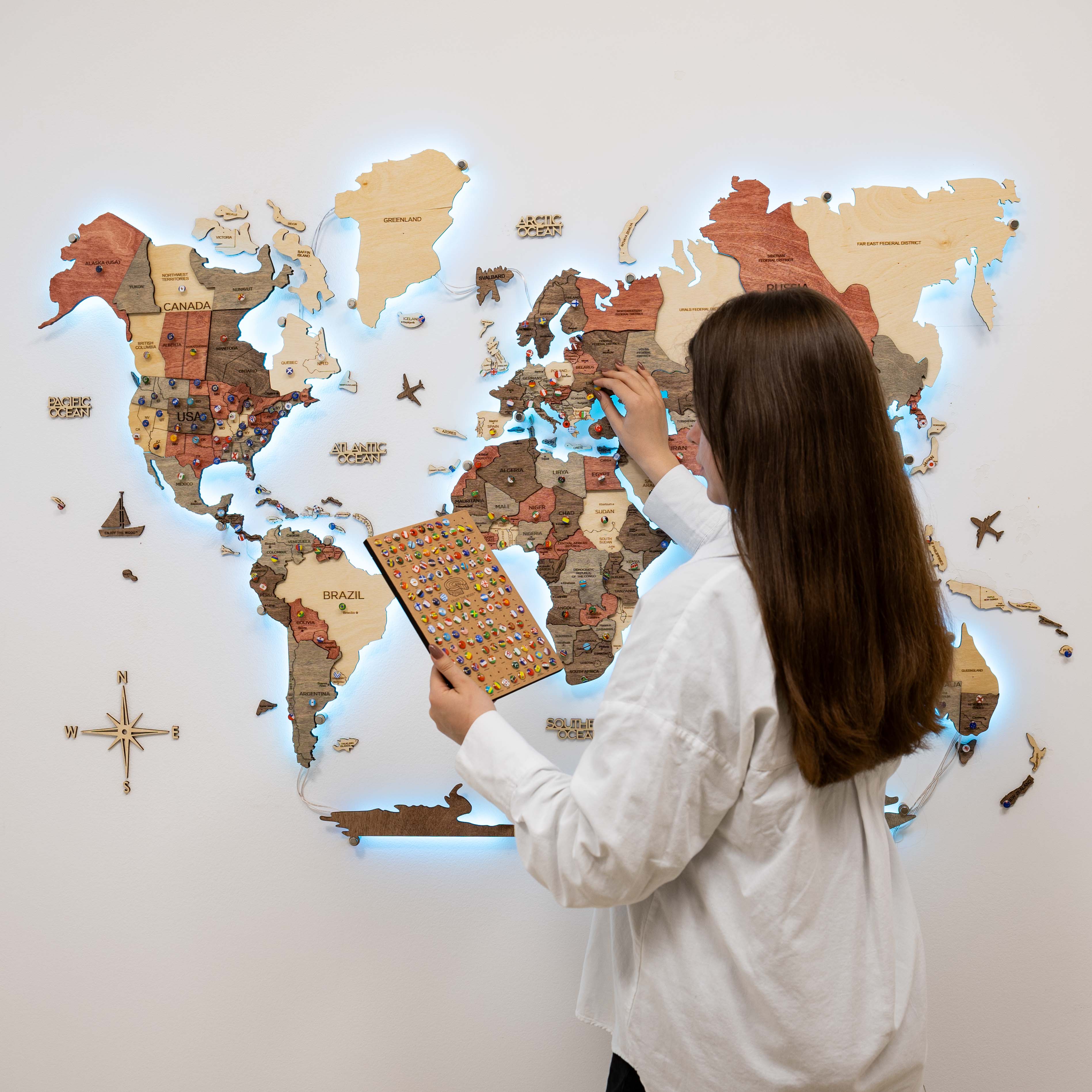3D LED Wooden World Map 3.0 Fusion with interactive backlight mounted on a modern living room wall