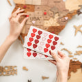 Close-up of red and pink heart-shaped wooden love pins on a wall-mounted travel map