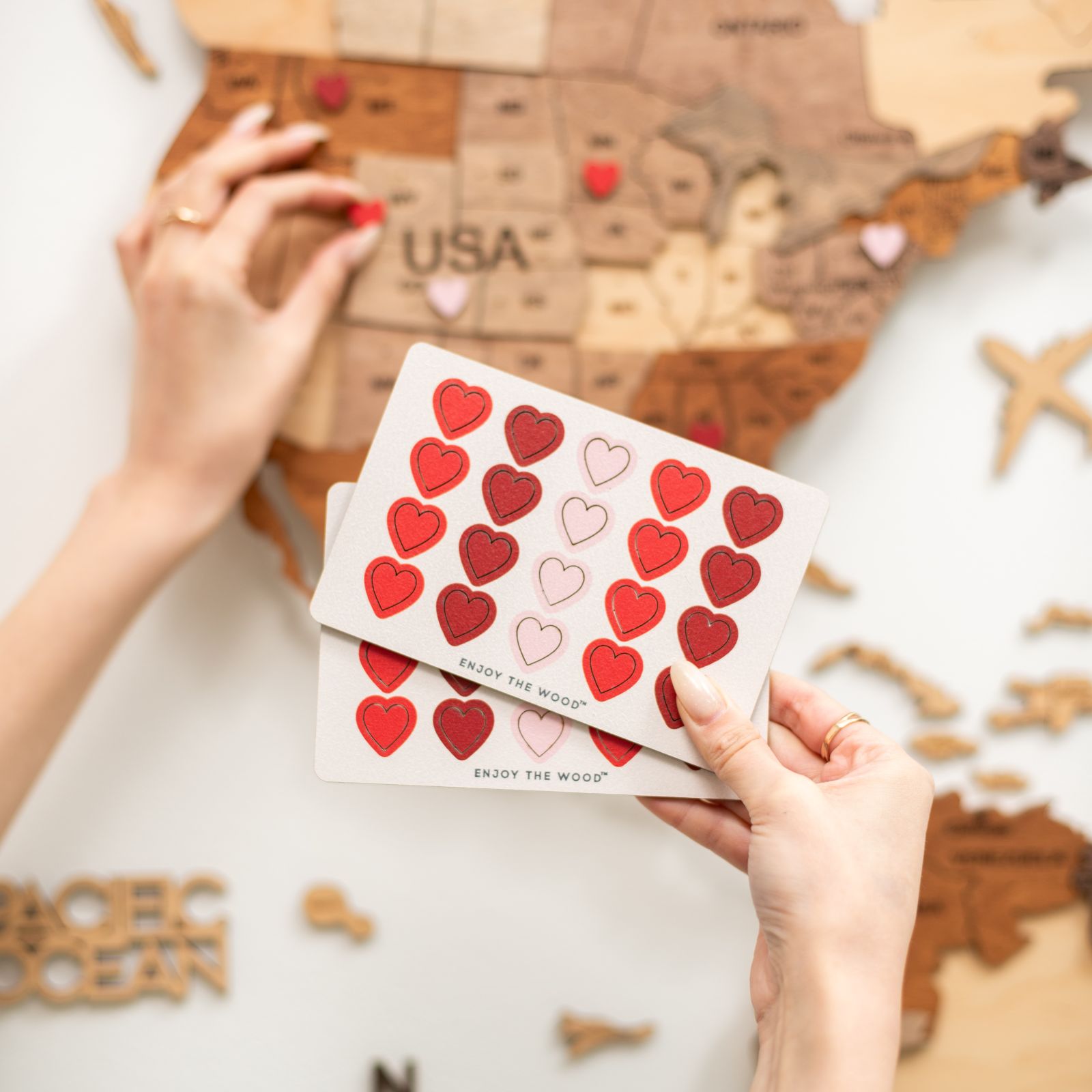 Close-up of red and pink heart-shaped wooden love pins on a wall-mounted travel map