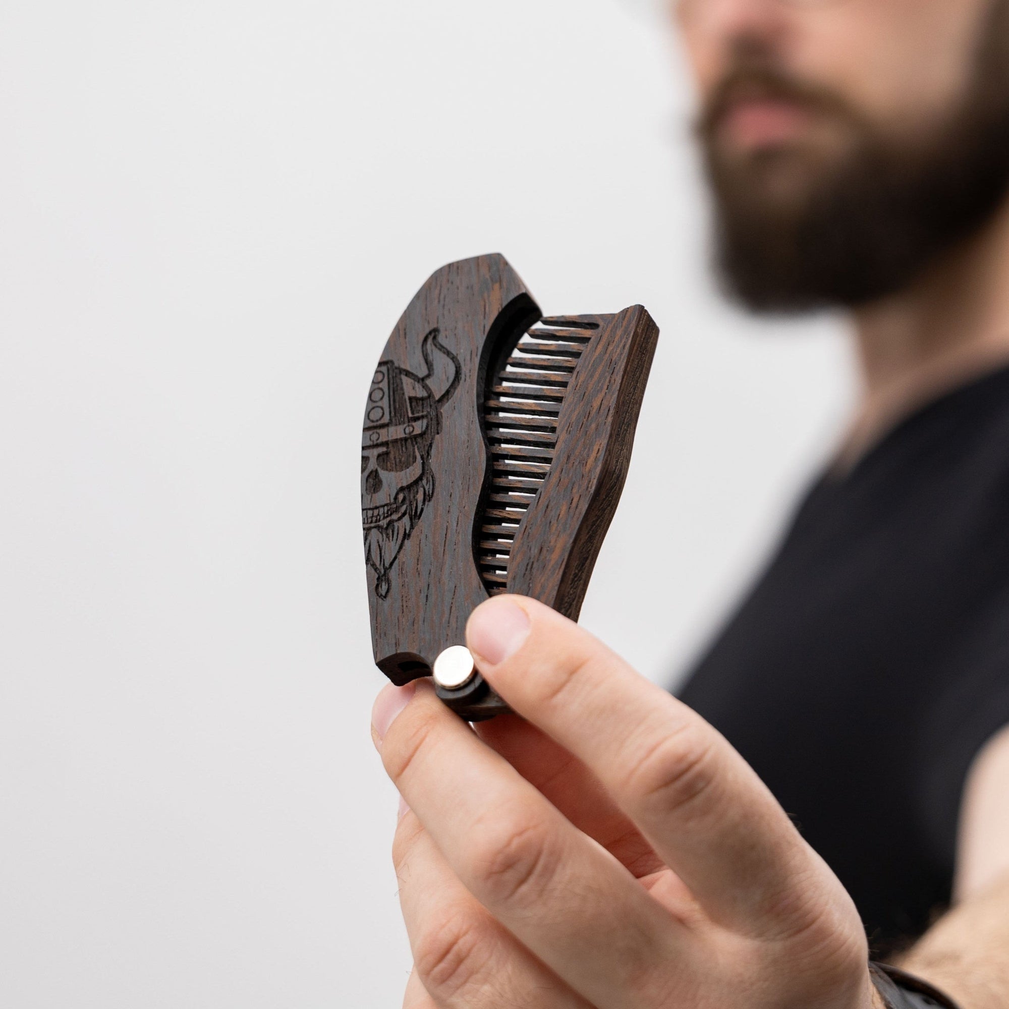 Close up of a handcrafted wooden beard comb featuring an intricate Viking motif engraving.