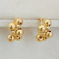 A pair of gold-toned woven bubble design hoop earrings displayed on a velvet jewelry stand and modeled on a person.