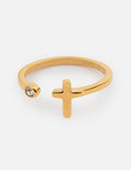 Delicate gold-toned ring with a wrapped cross design and a small bezel-set crystal, viewed from a close-up angle.