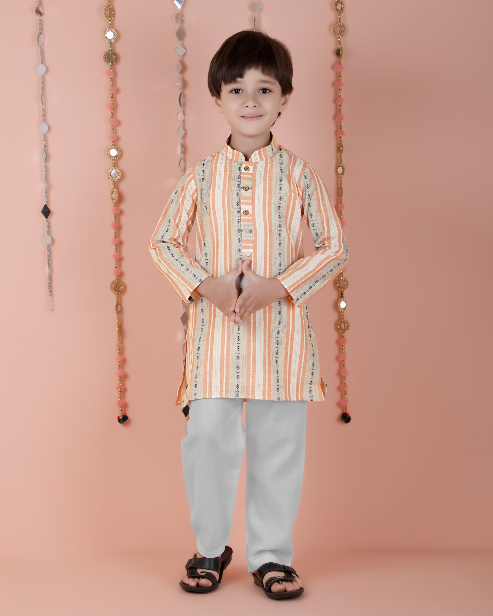 Young child wearing an orange striped cotton kurta and matching pyjama set