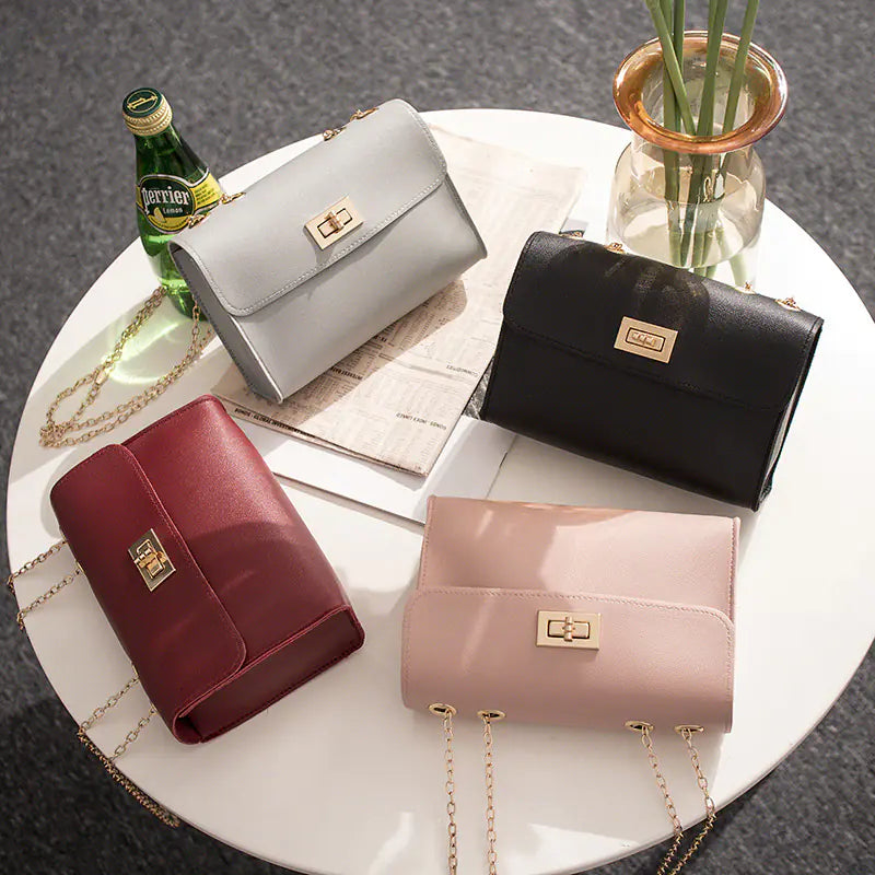 Set of four small square PU leather shoulder bags in black, grey, pink, and burgundy with gold chain straps.