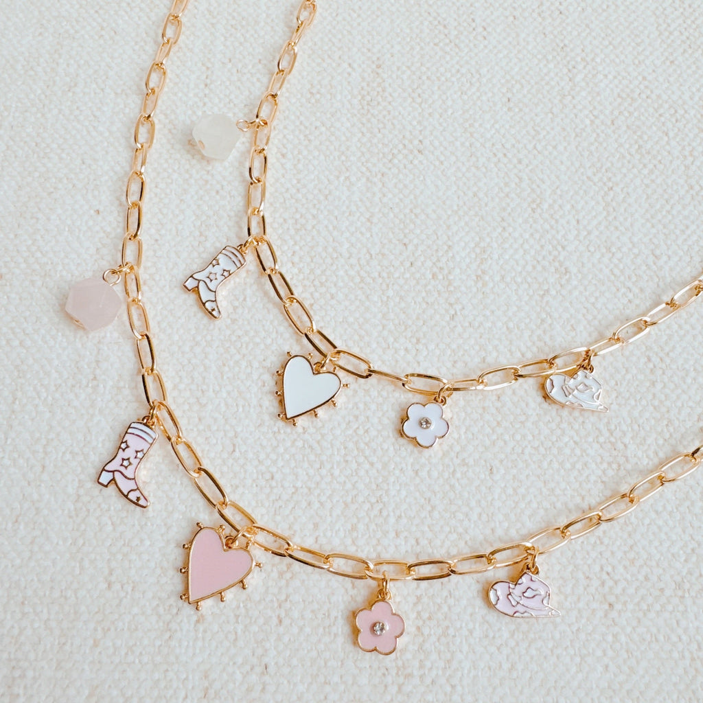 Yee-haw Heart Multi Charm Necklace with gold chain and western style charms on a textured background