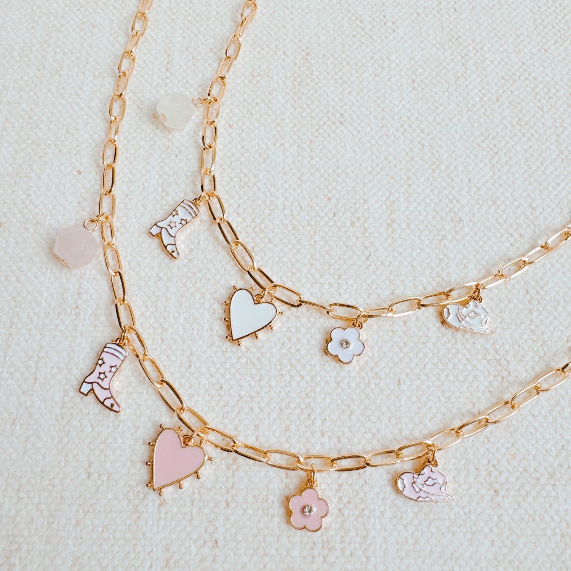 Yee-haw Heart Multi Charm Necklace with gold chain and western style charms on a textured background