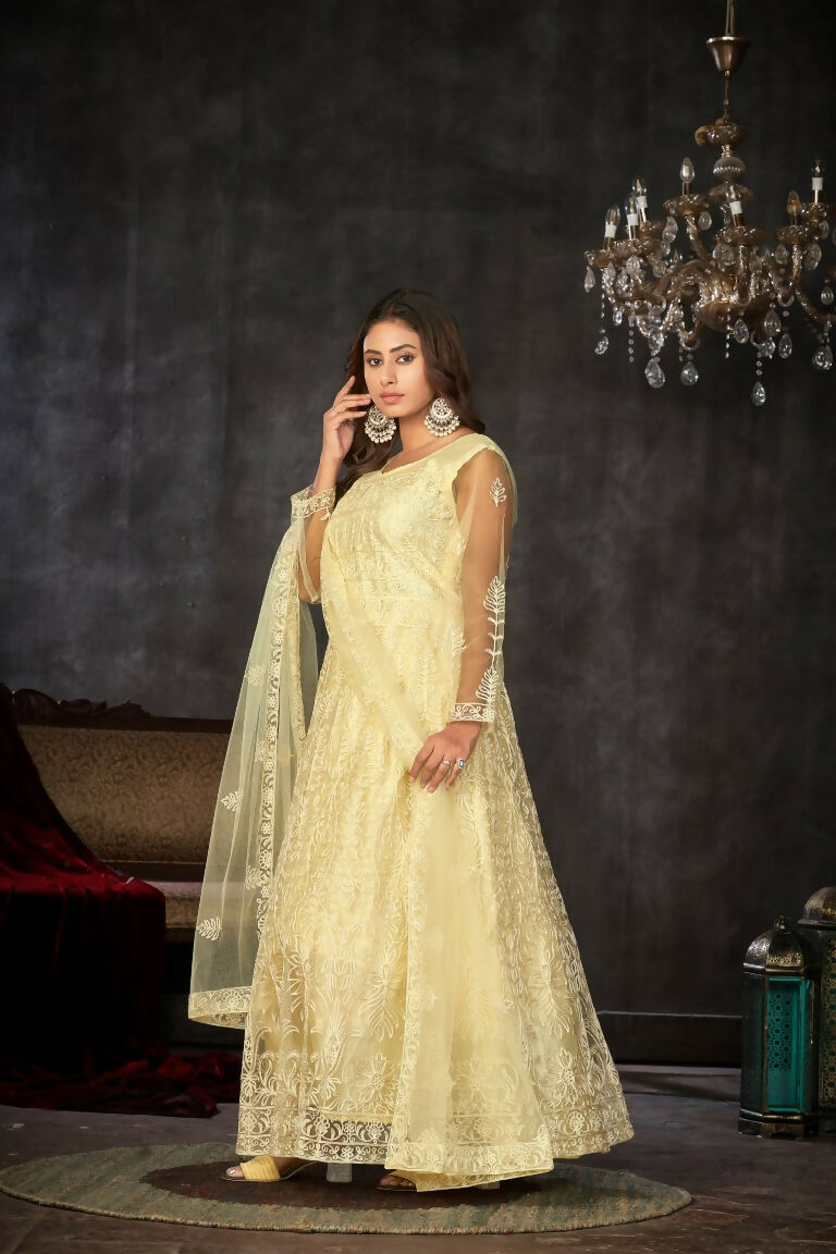 Woman wearing a cream colored net embroidered Anarkali suit with matching pants and dupatta