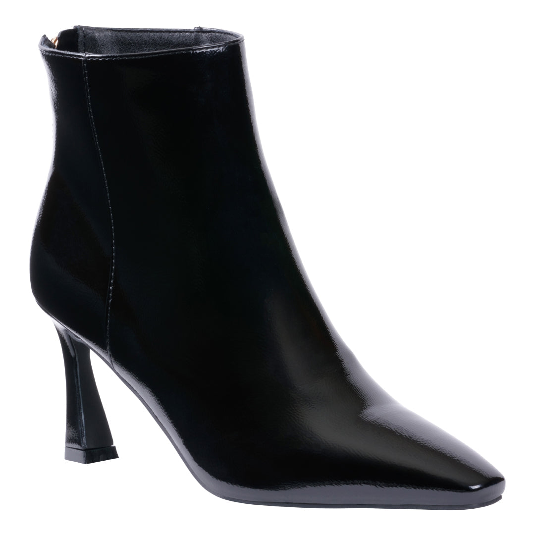 Side view of a glossy black pointed toe ankle bootie with a flared heel.
