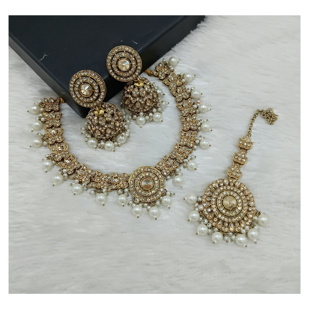 Elegant cream stone work necklace set featuring matching earrings and maang tikka on a clean background.