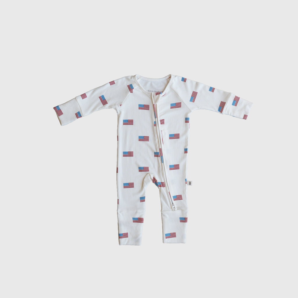 Baby wearing white, red, and blue Americana print ribbed bamboo zip pajamas