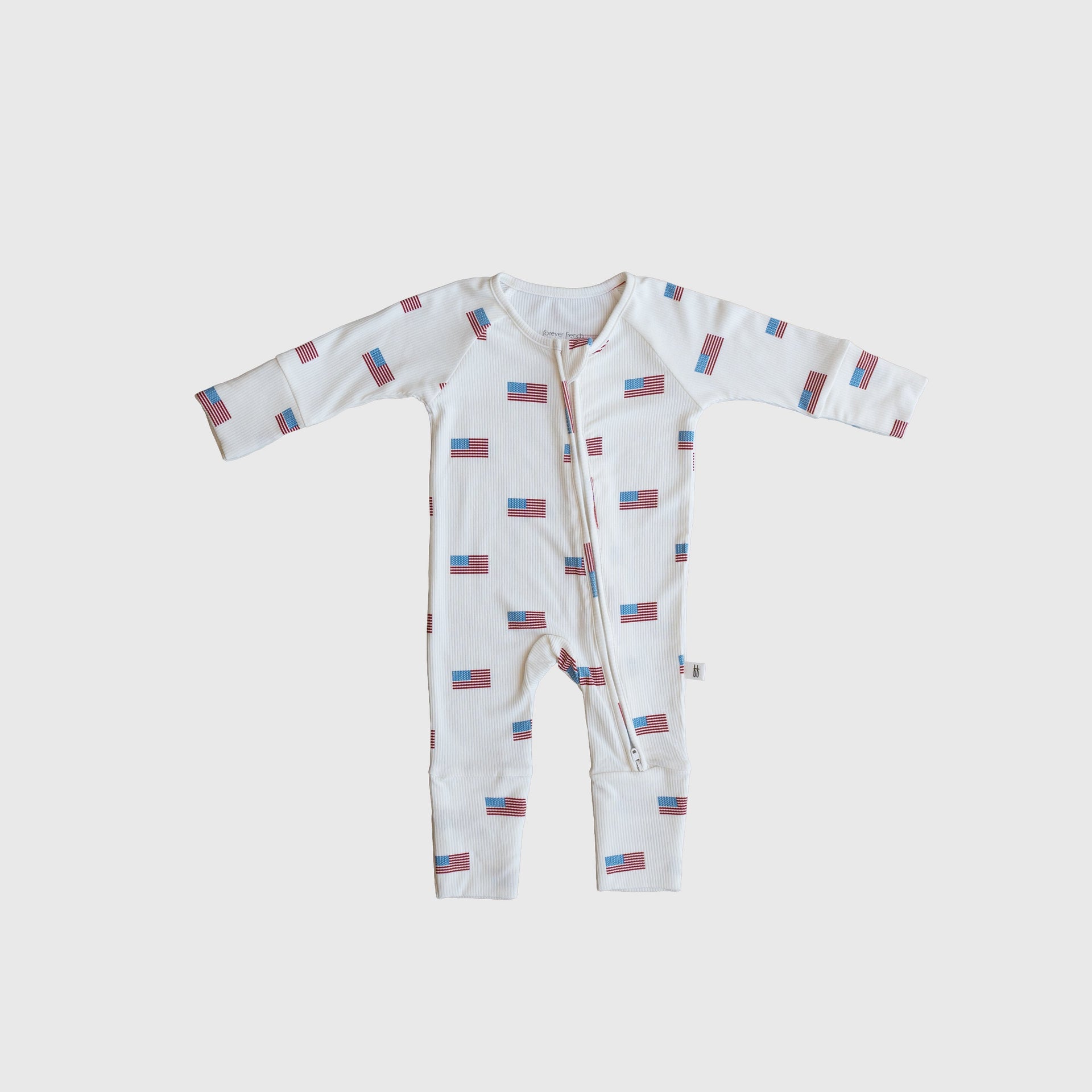 Baby wearing white, red, and blue Americana print ribbed bamboo zip pajamas