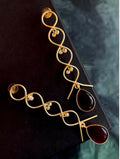 Close up of elegant cherry red Monalisa stone zigzag gold earrings on a display background