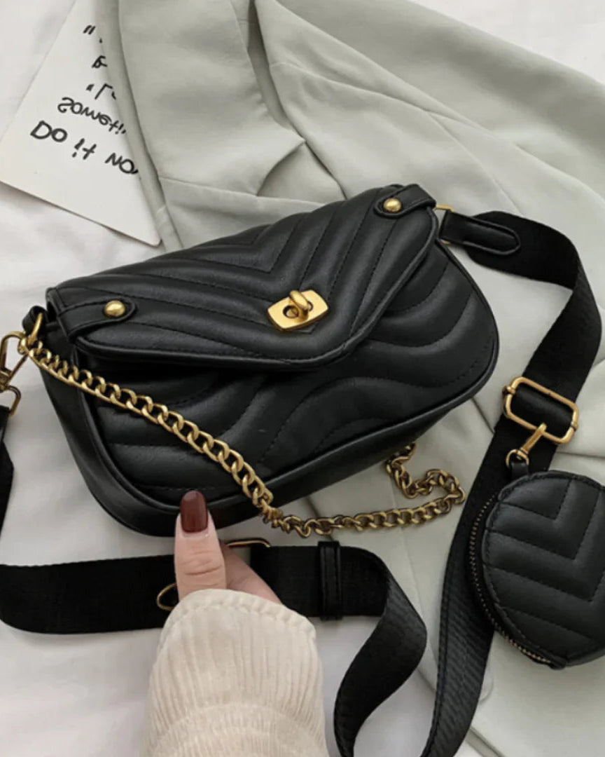 Black quilted handbag with gold chain and matching round pouch on a light background