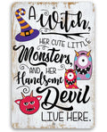 Decorative metal Halloween sign featuring a witch hat, colorful monsters, and the text A Witch, Her Cute Little Monsters, and Her Handsome Devil Live Here.