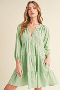 Model wearing a notched balloon sleeve tiered mini dress in a summer setting
