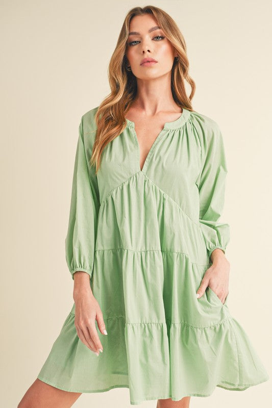 Model wearing a notched balloon sleeve tiered mini dress in a summer setting