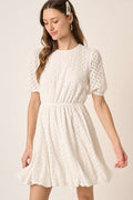 Chic mini dress with a delicate eyelet pattern, round neck, and romantic puff sleeves.