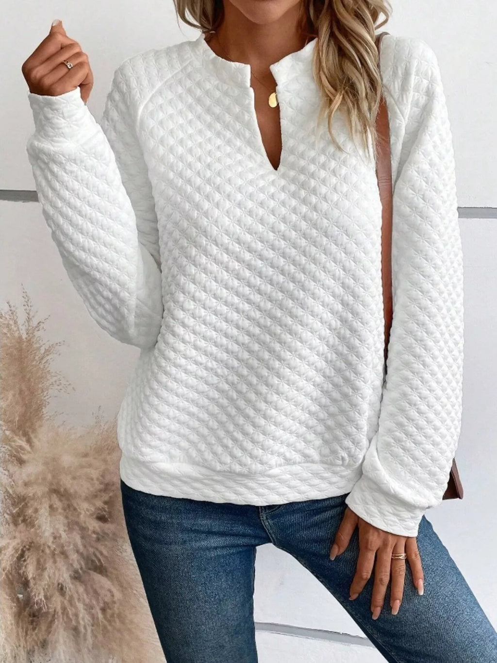 Woman wearing a white long sleeve sweatshirt with a notched neckline and quilted texture