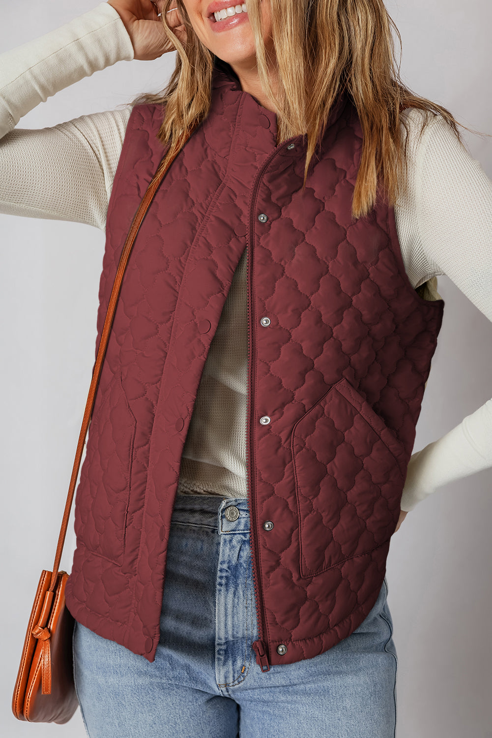 Women wearing a quilted zip-up snap button vest in a solid autumnal tone, layered for a casual, sporty look.
