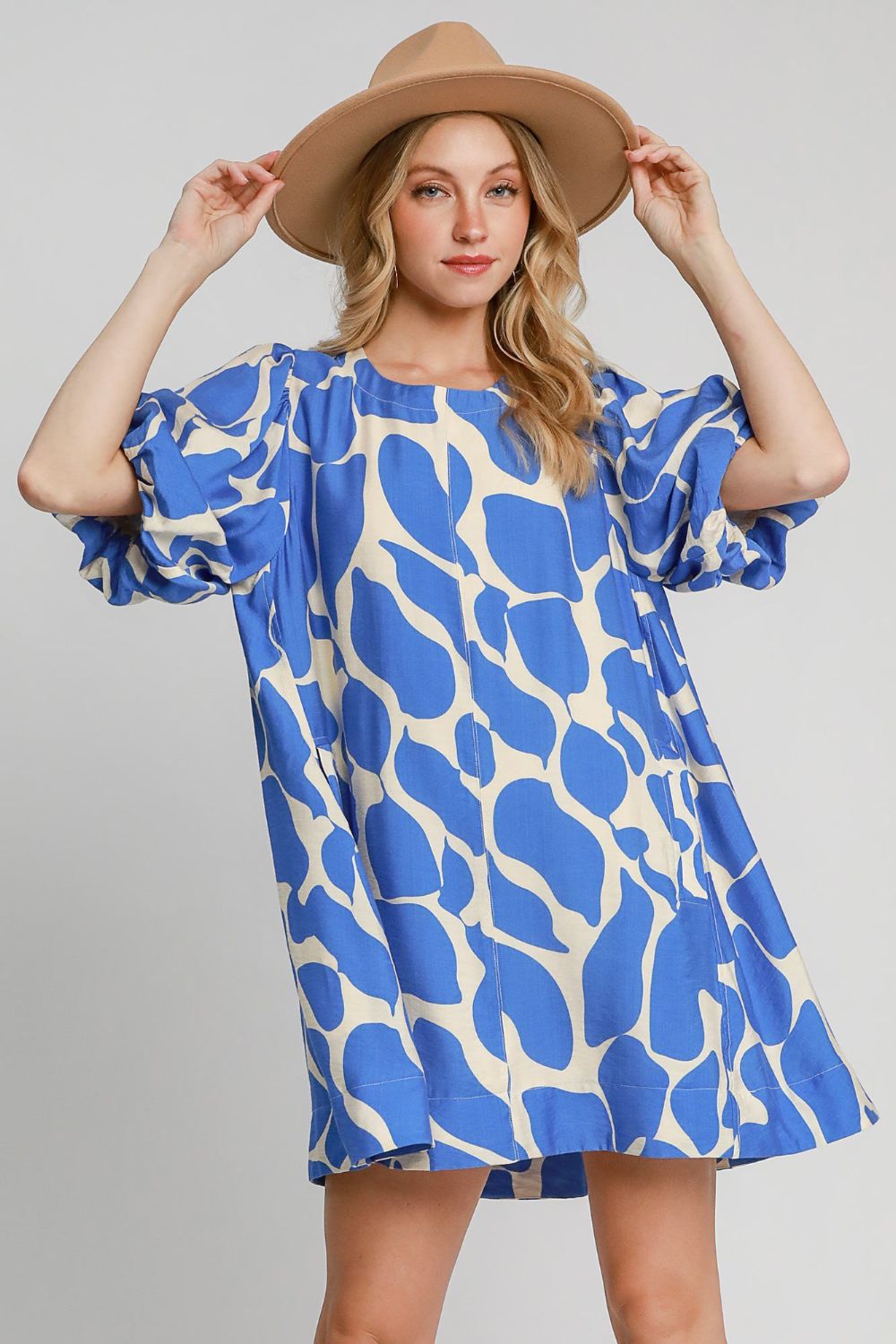 Woman wearing a two-tone abstract print dress with trendy puff sleeves.