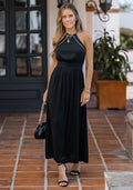 Woman wearing a black high neck long sleeve beaded maxi dress with an open back design.