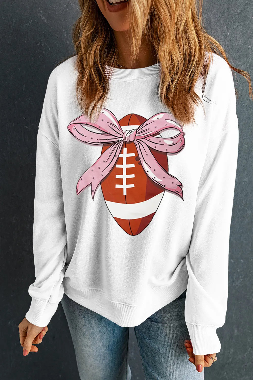 Woman wearing a football-inspired round neck long sleeve knit sweatshirt in white, pink, or brown