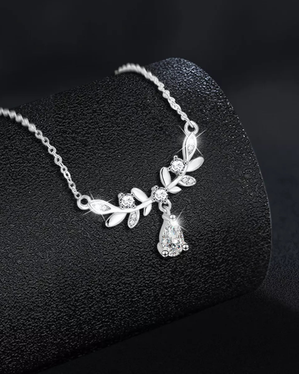 Silver necklace with leaf design on a black textured surface