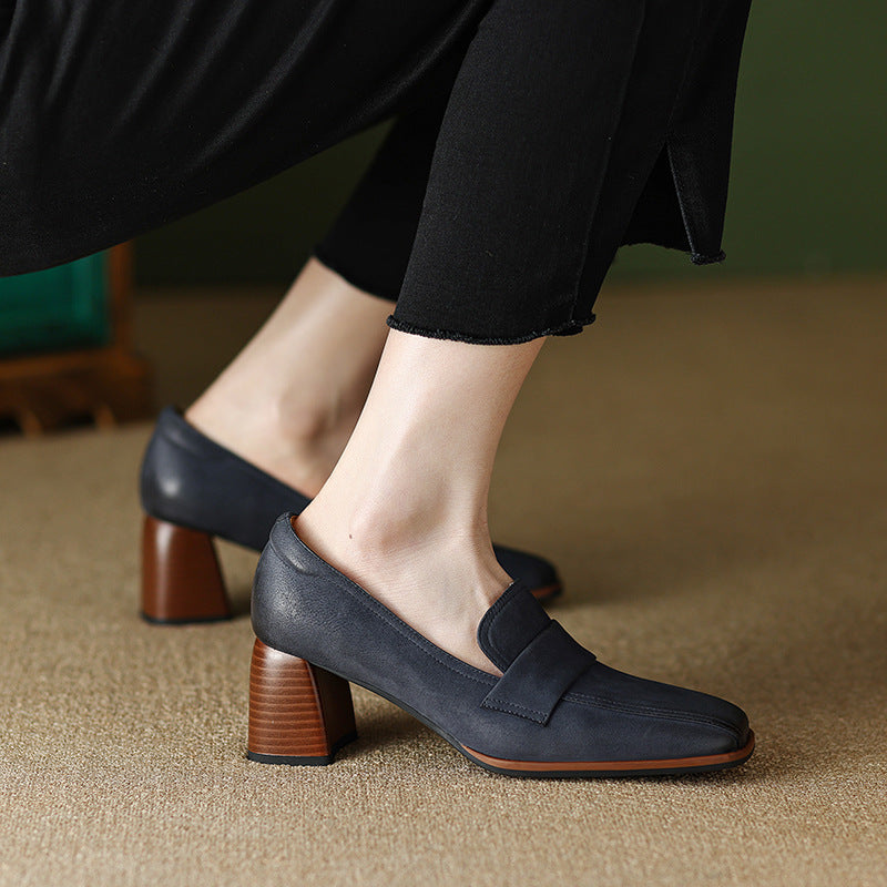 Women wearing navy and brown square toe sheepskin chunky heel pumps on a neutral surface.