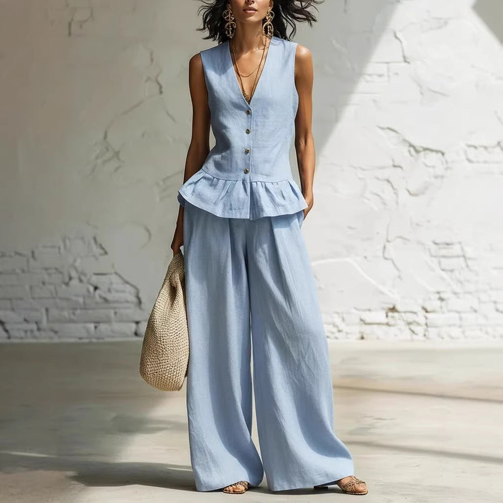 A woman wearing a two-piece summer set consisting of a blue sleeveless button-down vest with a ruffled hem and matching wide-leg trousers.