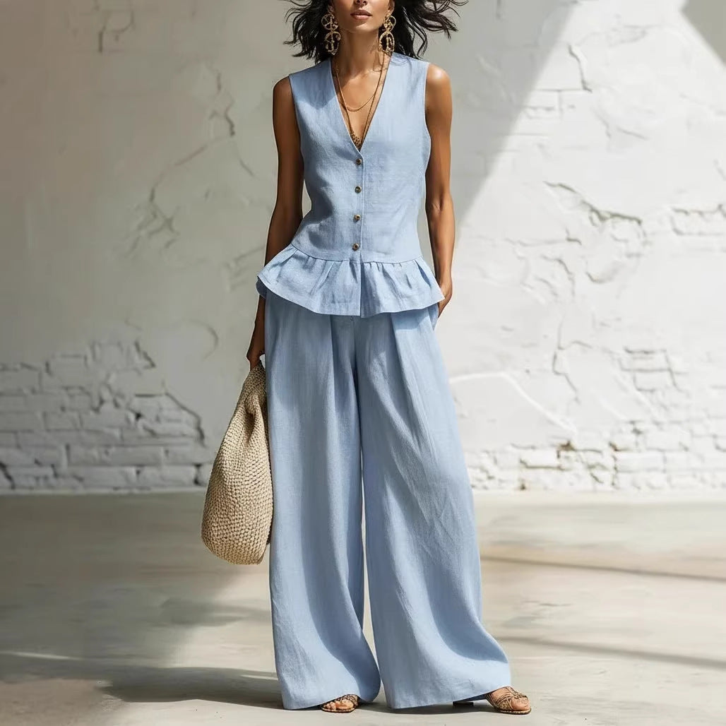 A woman wearing a two-piece summer set consisting of a blue sleeveless button-down vest with a ruffled hem and matching wide-leg trousers.