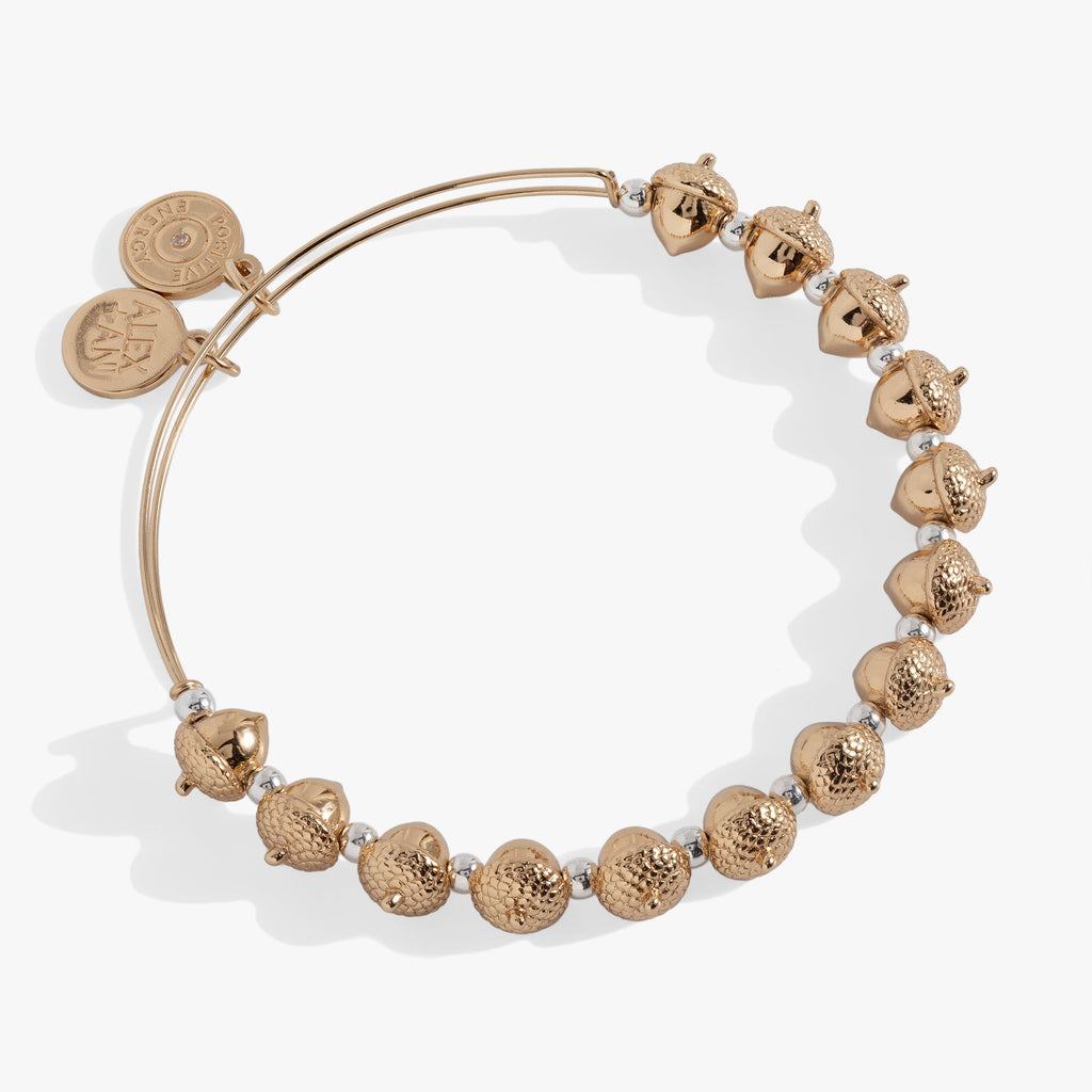 A close-up of a gold and silver acorn beaded bangle on a neutral background, highlighting the woodland-inspired design.