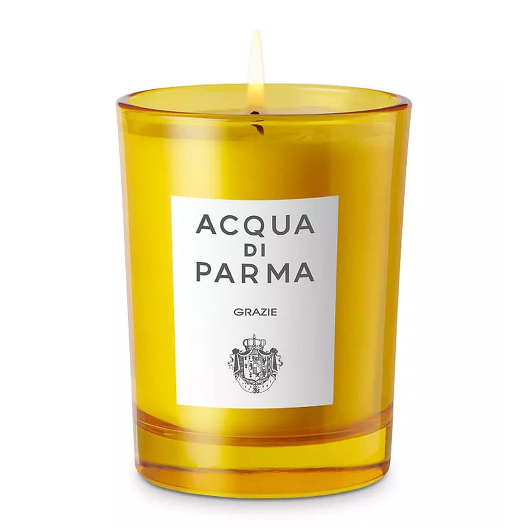 Acqua di Parma Grazie scented candle in a vibrant yellow glass jar with a white label on a minimalist surface.