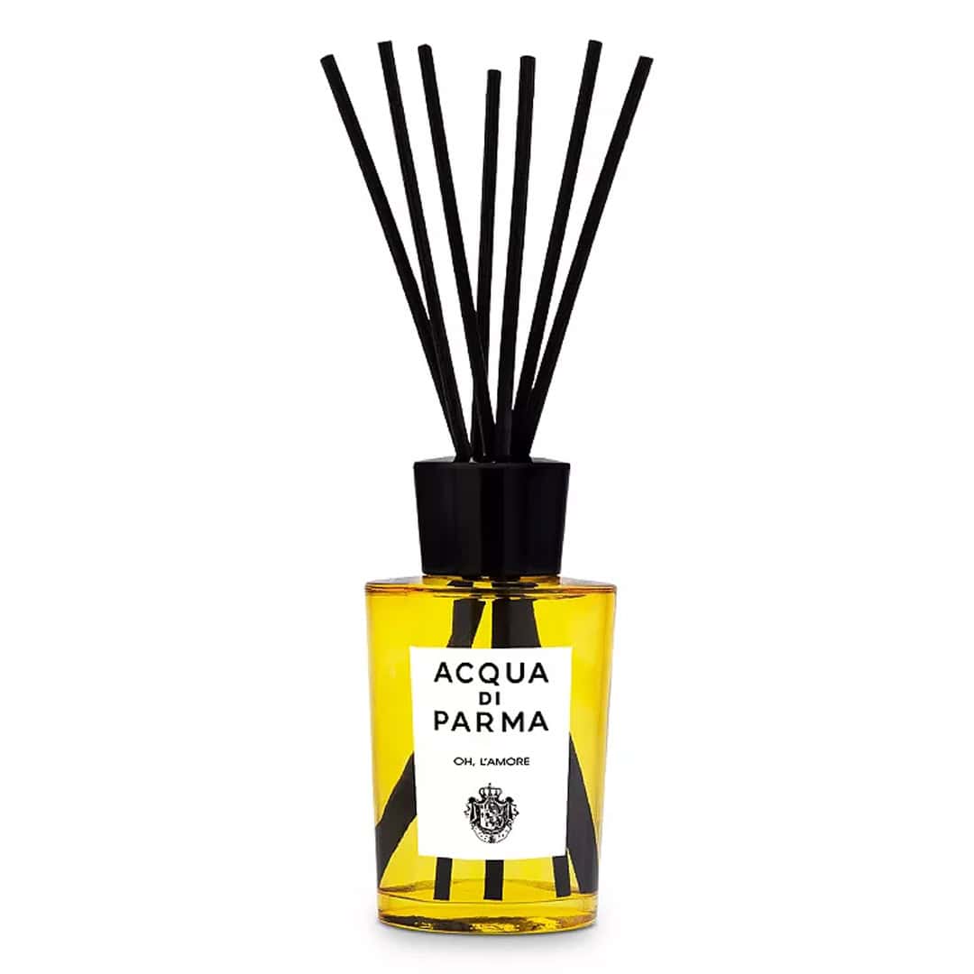Modern glass room diffuser with amber yellow oil and black accents in a minimalist style