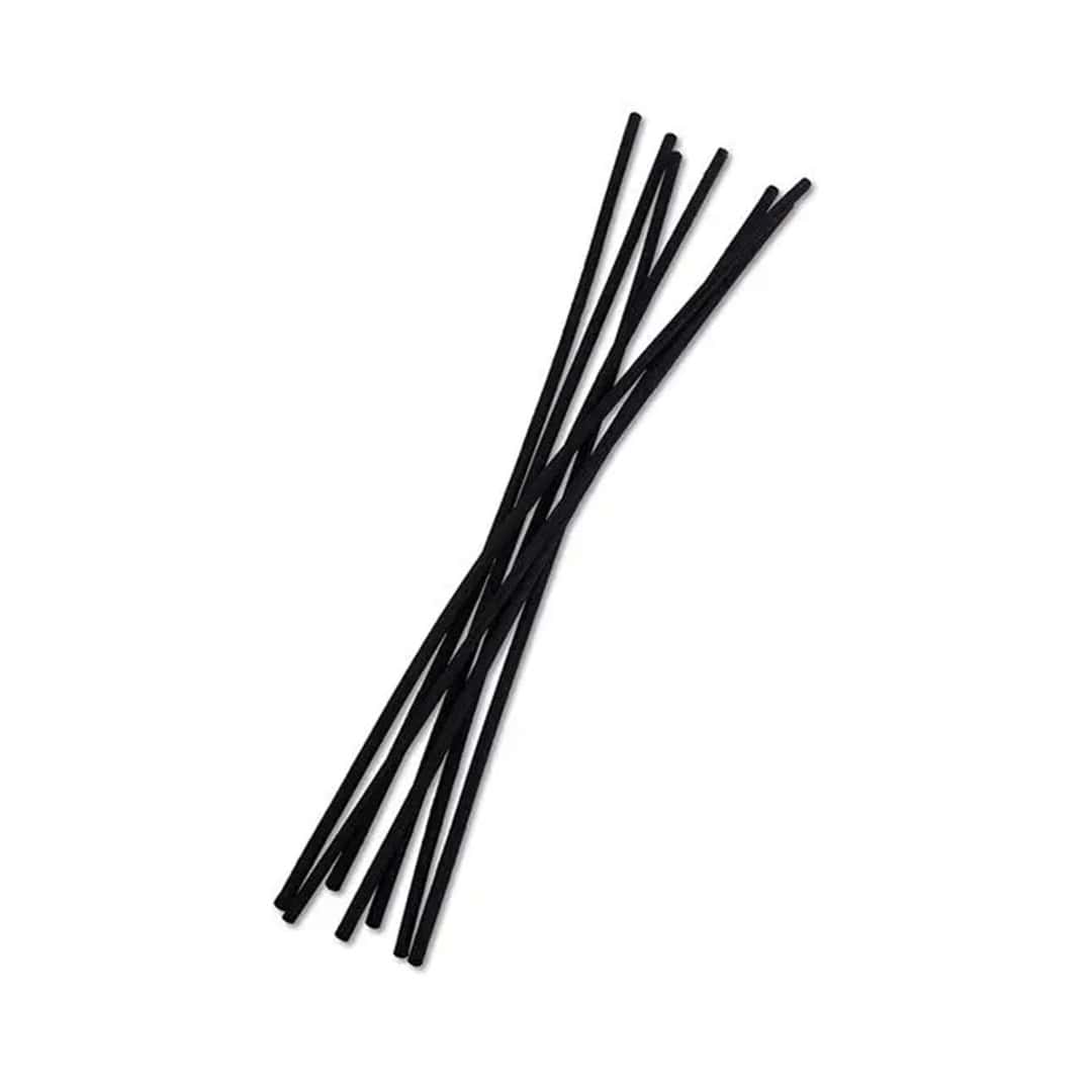 Set of 7 sleek black rattan diffuser reeds arranged in a modern home setting.