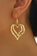 Yaretzi gold-tone double heart dangle earrings worn on a model, featuring a polished finish.