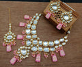 A beautiful baby pink kundan necklace set with gold-plated polish on a clean background