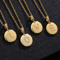 A close-up of a gold-plated initial disc necklace featuring a sparkling zircon letter pendant.