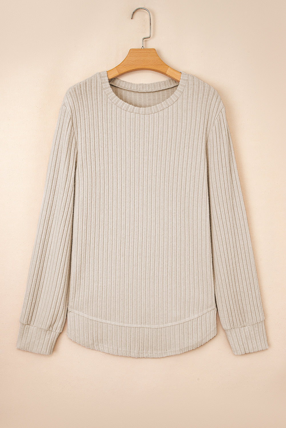 Model wearing a minimalist beige ribbed knit round neck top with high-stretch fabric texture.