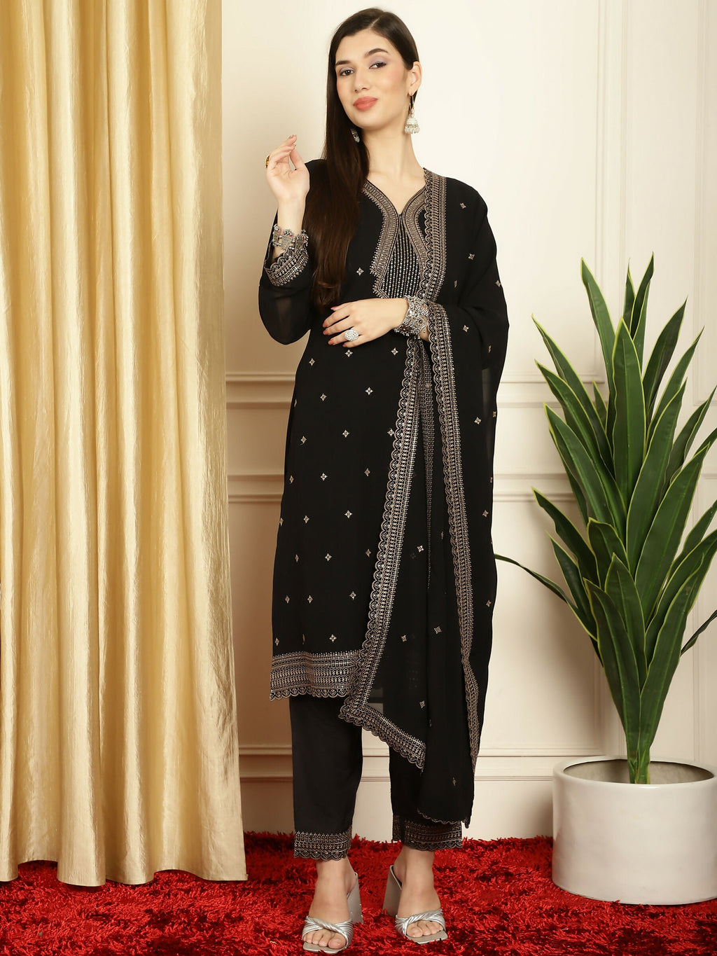 A woman wearing a black georgette straight kurta with intricate Resham thread and sequin embroidery, styled with trousers and a dupatta.