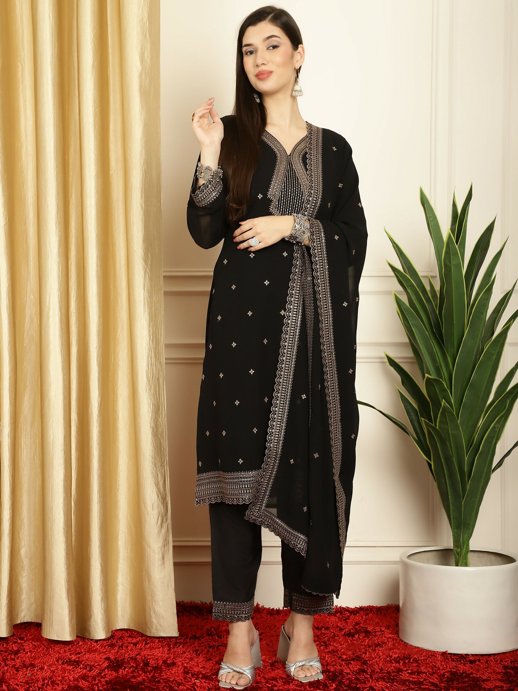 A woman wearing a black georgette straight kurta with intricate Resham thread and sequin embroidery, styled with trousers and a dupatta.