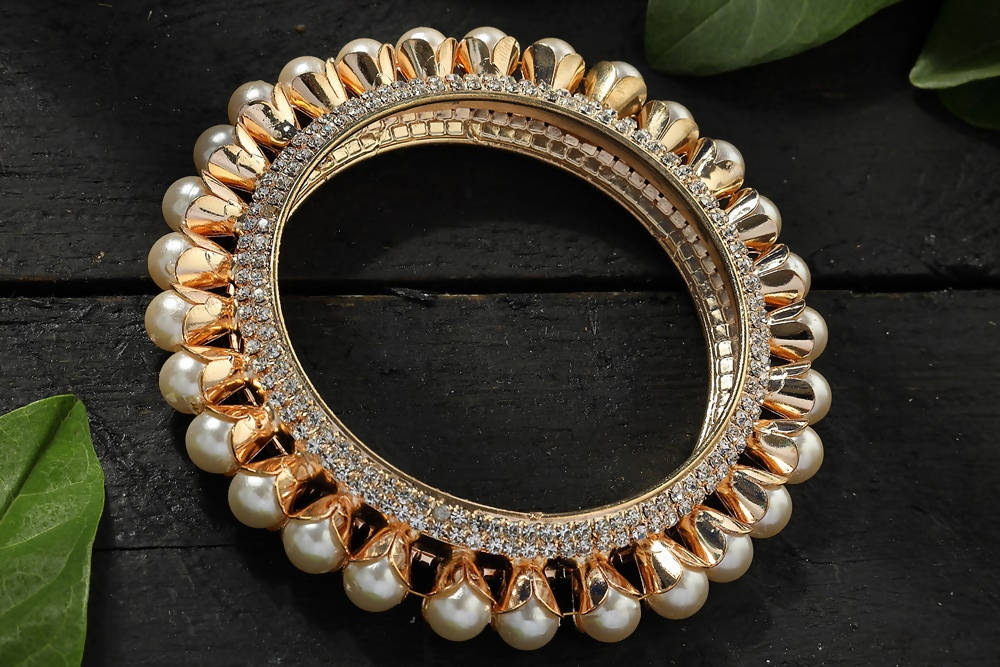 Close-up of golden bangle set with off-white accents and American Diamond stones