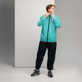 A man wearing a bright teal windbreaker jacket with a hood, featuring a black front zipper and graphic logos on the chest and sleeve.